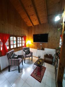 sala de estar con 2 sillas y TV de pantalla plana en Cabaña Ayelen en Esquel