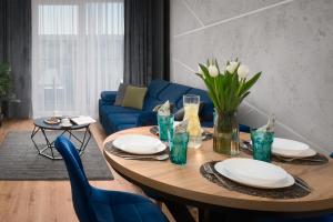 a living room with a table and a blue couch at Apartament Marina Loft & Spa Sagaris Dziwnów in Dziwnów