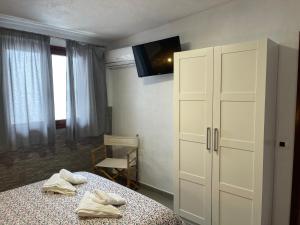 1 dormitorio con 1 cama, armario y TV en Apartamentos Finca Wapa en Frontera