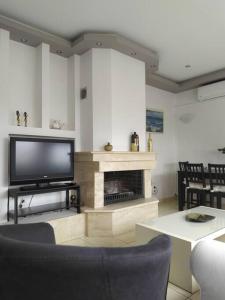 sala de estar con TV y chimenea en Kritharia Guesthouse Volos, en Kritharia