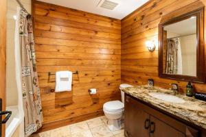 a bathroom with wooden walls and a toilet and a sink at ALTITUDE 170-2 / PRIVATE Hot Tub on HUGE Terrace in Mont-Tremblant