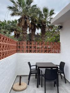 um pátio com uma mesa, cadeiras e palmeiras em Apartamentos Finca Wapa em Frontera