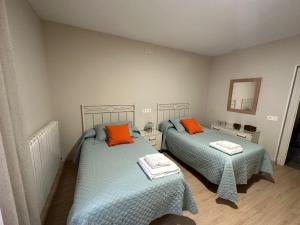 1 Schlafzimmer mit 2 Betten und orangefarbenen Kissen in der Unterkunft Casa Janices in Artajona