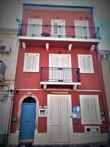 a red building with two blue doors and a balcony at Vecchia Paradiso - A un passo dal Mare in Messina