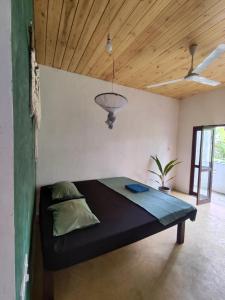 a bed in a room with a wooden ceiling at Tiger Villa in Midigama East