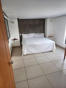a bedroom with a white bed and a tiled floor at MOTEL PREMIER in Guadalajara