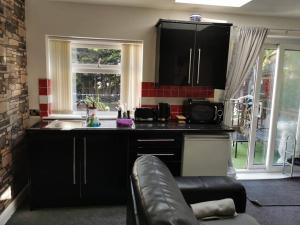 a kitchen with black cabinets and a sink and a couch at Wimpole Lounge in Oldham
