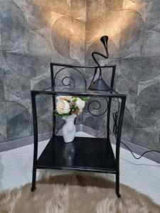 einen schwarzen Tisch mit einer Vase aus Blumen und einer Lampe in der Unterkunft OnlyStudio in Zadar