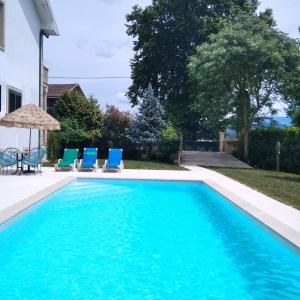 einen Pool mit zwei blauen Stühlen und einem Sonnenschirm in der Unterkunft Villa Garden & Pool - Alojamentos in Celorico de Basto