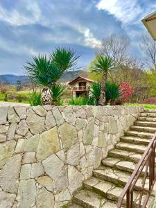 a stone wall with palm trees and a house at Ojakh Resort in Ijevan