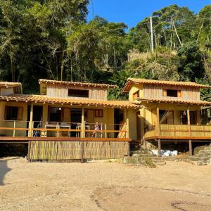 une maison avec une terrasse couverte et une personne debout sur la terrasse couverte dans l'établissement Chalé na Praia de Ponta Negra, à Ponta Negra