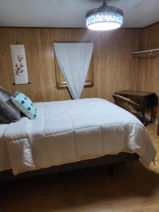1 dormitorio con 1 cama blanca, ventana y piano en Legend Rock Lodge, en South Kingstown