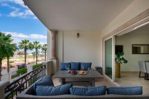 uma sala de estar com um sofá e uma mesa na varanda em Condo Maravilla - New luxurious condo 300mt from the beach em Cabo San Lucas
