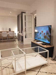a living room with a tv and a glass coffee table at Charmante villa proche de la gare et de Paris in Les Pavillons-sous-Bois