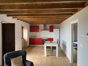 a room with a table and a kitchen with red cabinets at O Casa con vistas en Carnota in Lira