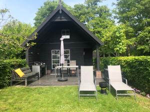 a black shed with a table and chairs in the grass at Polderhuus Galatheapolder in Achthuizen