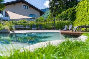 a pool with chairs and an umbrella next to a house at Ferienwohnungen Atz in Termeno