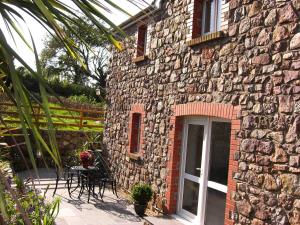 a stone building with a table and chairs in front of it at Burry Farm Cottage in Swansea