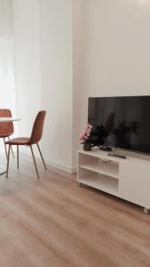 uma sala de estar com uma televisão e uma mesa e cadeiras em So Fine Petruzzelli flat em Bari