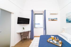 a room with a bed with a desk and a tv at FRENNESIA Amalfi Coast in Atrani