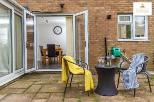 a patio with chairs and a table with a clock at 4 Bed House Stevenage SG1 Free Parking & Wi-Fi Business & Families Serviced Accommodation by White Orchid Property Relocation in Stevenage