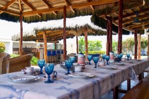uma mesa longa com óculos azuis e pratos nela em CASA PUNTA CARNERO em Presidente Tamayo