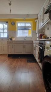 uma cozinha com armários brancos, um lavatório e uma janela em Lovely 5-bed home with free parking and garden em Addington