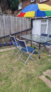 due sedie e un tavolo con ombrellone in un cortile di Lovely 5-bed home with free parking and garden a Addington