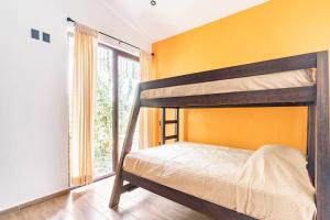 Mid Town Tapalpa في تابالبا: غرفة نوم مع سرير بطابقين مع جدار برتقالي