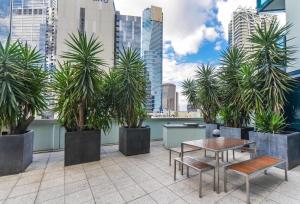 a patio with palm trees and a table and bench at StayCentral - Cityviews on City Road Southbank in Melbourne