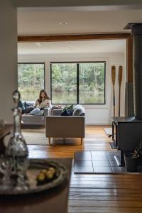 a woman sitting on a couch in a living room at Naivasha Cottage in Deloraine