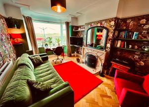 Liverpool - Cosy Jazzy Beach Home! في Waterloo: غرفة معيشة مع أريكة خضراء وسجادة حمراء