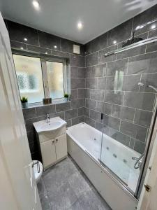 a bathroom with a bath tub and a sink at Paul Properties in Ruislip