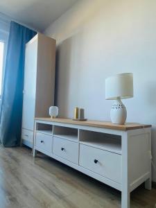 a white dresser with a lamp on top of it at Apartament Długie Ogrody 54 in Gdańsk