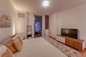 a bedroom with a large bed and a flat screen tv at Queen Apartments Belgrade Waterfront in Belgrade +32 photos