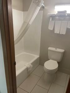 a white bathroom with a toilet and a bath tub at Royal Inn & Suites in Mountain Grove