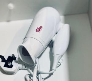 a white hairdryer hanging on a wall at Stay Inns in Birmingham