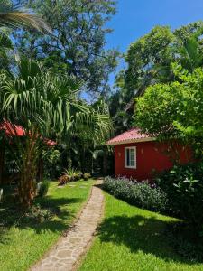 una casa roja en medio de un jardín en Cabaña Villa Victoria, en El Valle de Antón
