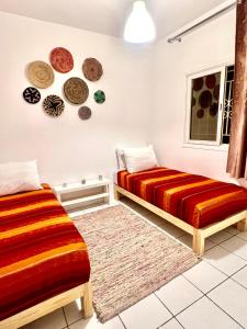 - 2 lits dans une chambre avec des plaques murales dans l'établissement Duplex Calme cosy 5 minutes du centre d'Essaouira, à Essaouira