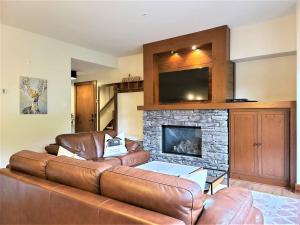 a living room with a leather couch and a fireplace at Étoile Du Matin 1510-19/Perfect for large Family in Mont-Tremblant