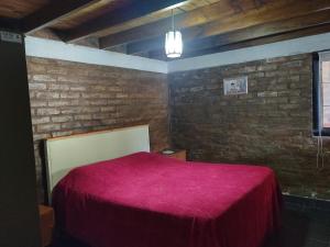 a bedroom with a red bed in a brick wall at LC House in Potrerillos
