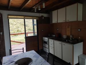 a kitchen with white cabinets and a table and a window at LC House in Potrerillos