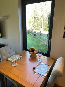 a wooden table with glasses and a bowl of fruit on it at Otters End in Dilham