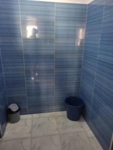 a bathroom with a blue tiled wall with a trash can at Peaceful Apartment in Al Hoceïma