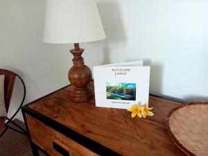a book on a table with a lamp and a flower at Mataiarii lodge in Papara
