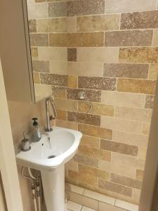 baño con lavabo y pared de ladrillo en Fully Equipped 4 Bedroom House with large Garden, en Hendon