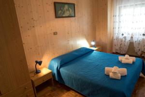 a bedroom with a blue bed with two towels on it at Appartamenti Patrizia in San Pietro di Cadore
