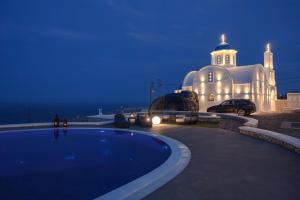 a villa with a swimming pool in front of a building at SANTORINI GRAND LUXURY VILLAS in Imerovigli