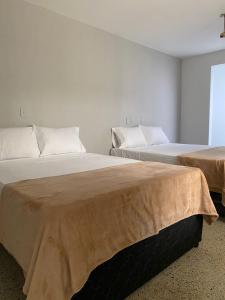 duas camas sentadas uma ao lado da outra num quarto em Aparta Hotel Mediterráneo Estadio em Medellín