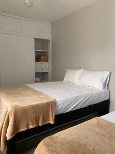 una camera con due letti con lenzuola bianche di Aparta Hotel Mediterráneo Estadio a Medellín